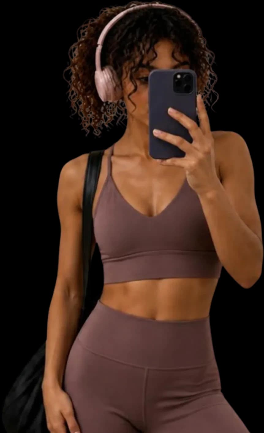 A woman taking a mirror selfie in workout clothes, wearing headphones